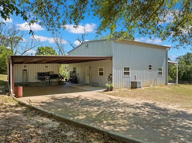 rear view of property with central air condition unit and driveway