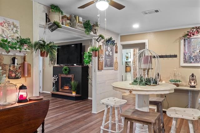 interior space with visible vents, recessed lighting, wood finished floors, a warm lit fireplace, and ceiling fan