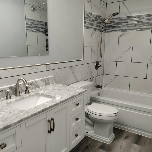 full bathroom featuring vanity, tiled shower / bath, hardwood / wood-style flooring, toilet, and tile walls