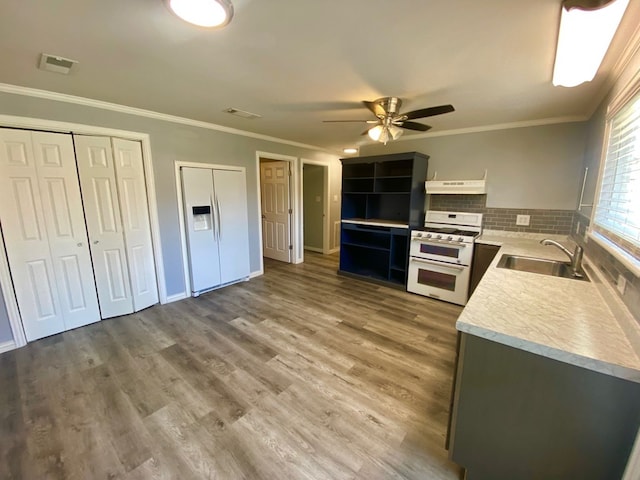 kitchen with white appliances, crown molding, sink, ceiling fan, and wood-type flooring