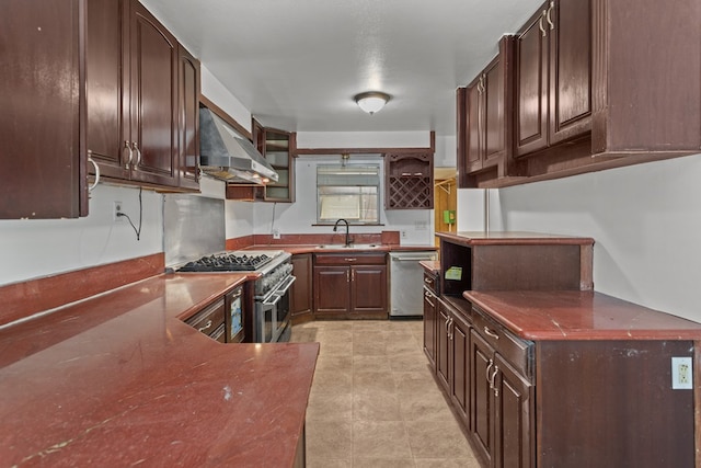 kitchen with appliances with stainless steel finishes, sink, dark brown cabinets, and wall chimney range hood