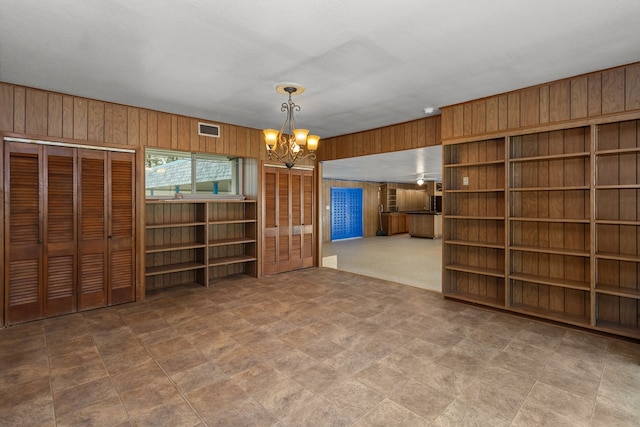 interior space with wood walls, a textured ceiling, and a notable chandelier