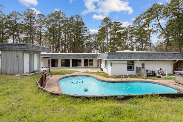 view of swimming pool with a lawn and a storage shed