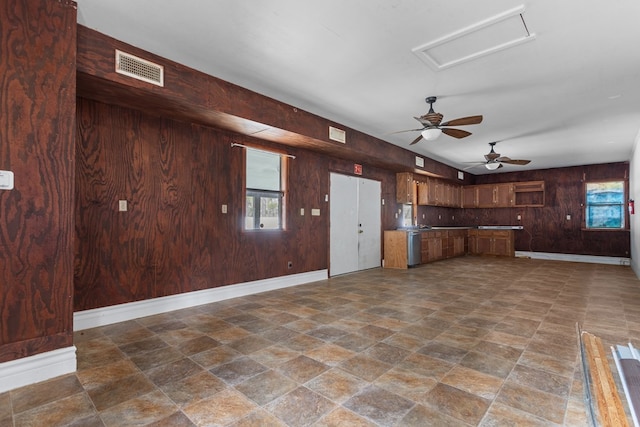 kitchen featuring wooden walls, dishwasher, and ceiling fan