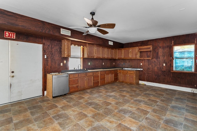 kitchen with dishwasher, ceiling fan, sink, and wooden walls