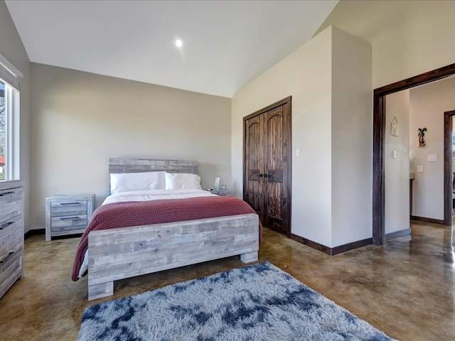 bedroom featuring finished concrete flooring, vaulted ceiling, and baseboards