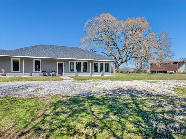 view of front of house with covered porch, a front lawn, and roof with shingles