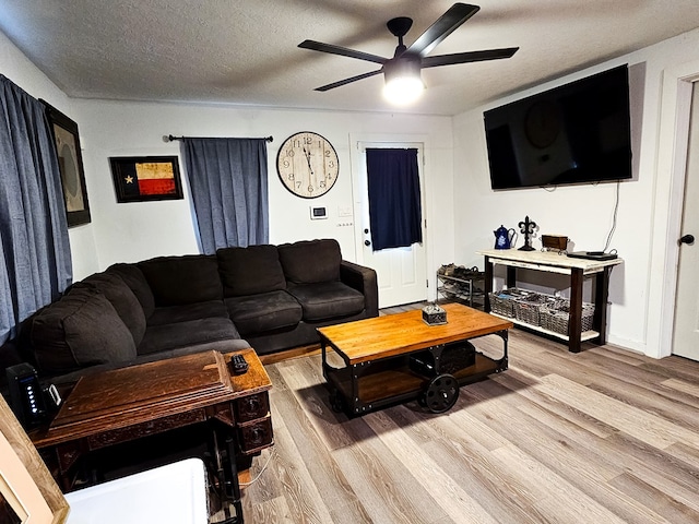 living room featuring ceiling fan, a textured ceiling, and light wood-type flooring