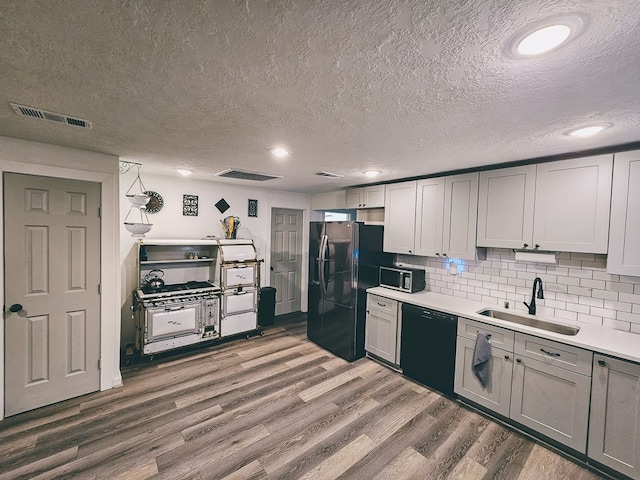 kitchen with dark hardwood / wood-style flooring, sink, a textured ceiling, and black appliances