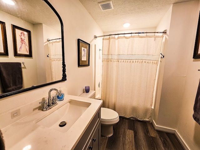 bathroom with hardwood / wood-style floors, a textured ceiling, toilet, vanity, and a shower with shower curtain