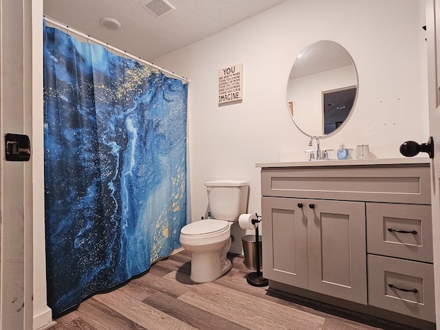 bathroom with a shower with curtain, vanity, a textured ceiling, hardwood / wood-style floors, and toilet