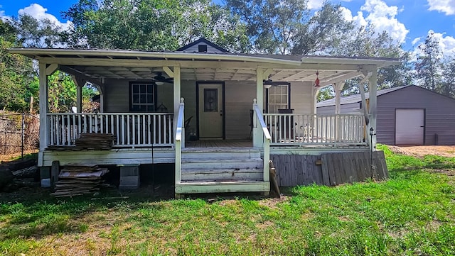 view of front of home featuring covered porch, ceiling fan, a storage shed, and a front yard