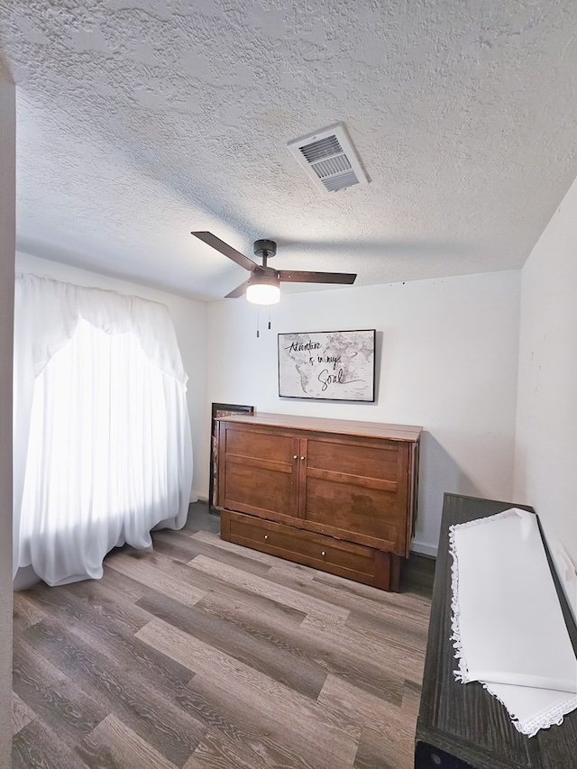 bedroom featuring ceiling fan, wood-type flooring, and a textured ceiling