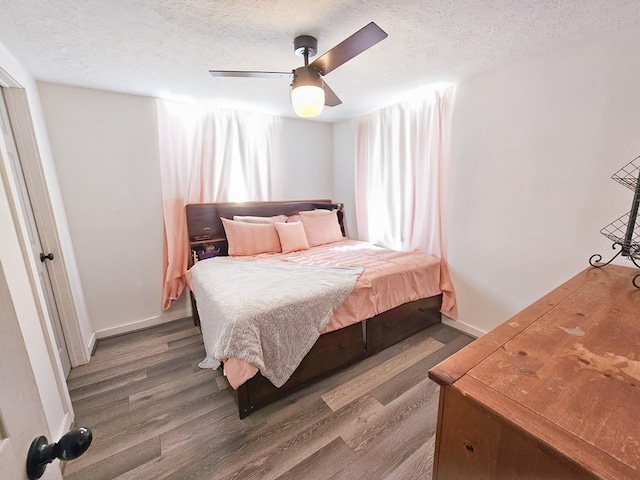 bedroom with ceiling fan, wood-type flooring, and a textured ceiling