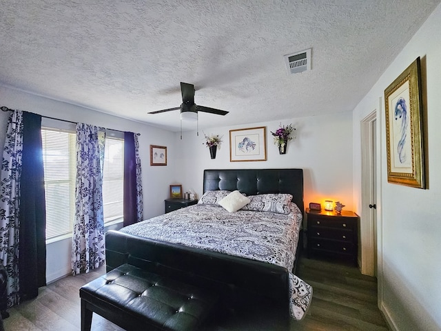 bedroom with ceiling fan, dark hardwood / wood-style flooring, and a textured ceiling