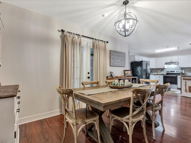 dining space featuring a textured wall, an inviting chandelier, dark wood-type flooring, a textured ceiling, and baseboards