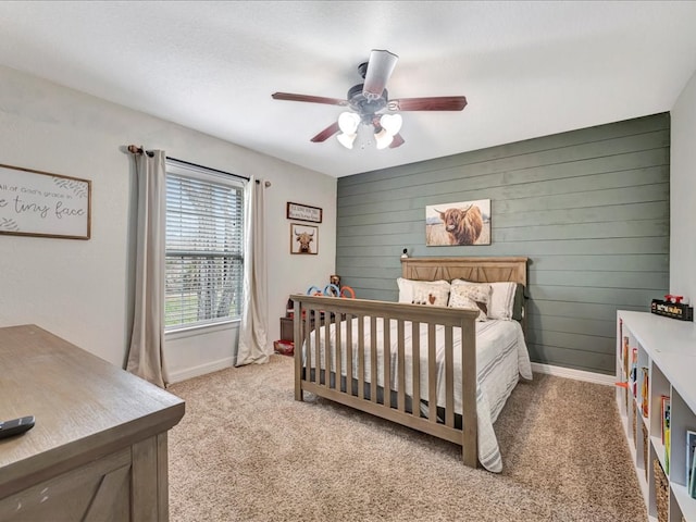 bedroom featuring light colored carpet, ceiling fan, wooden walls, and baseboards