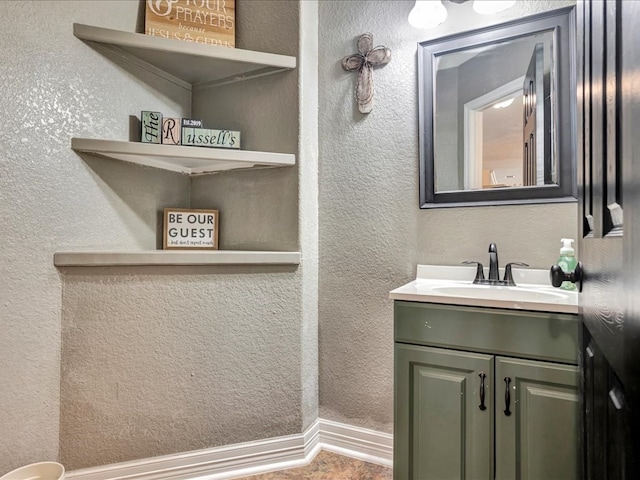 bathroom featuring a textured wall, baseboards, and vanity