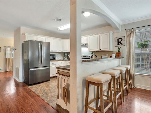 kitchen with visible vents, black microwave, freestanding refrigerator, and white cabinets