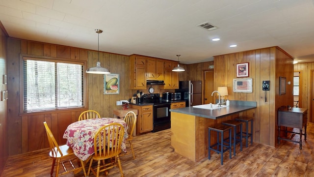 kitchen featuring a sink, black range with electric stovetop, light wood-type flooring, under cabinet range hood, and visible vents