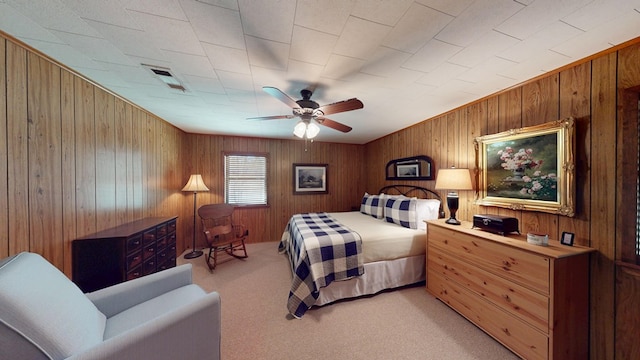 bedroom with a ceiling fan, wood walls, light colored carpet, and visible vents