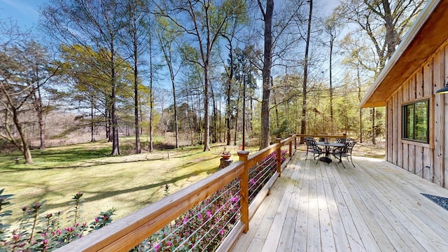 wooden terrace with a lawn and outdoor dining area