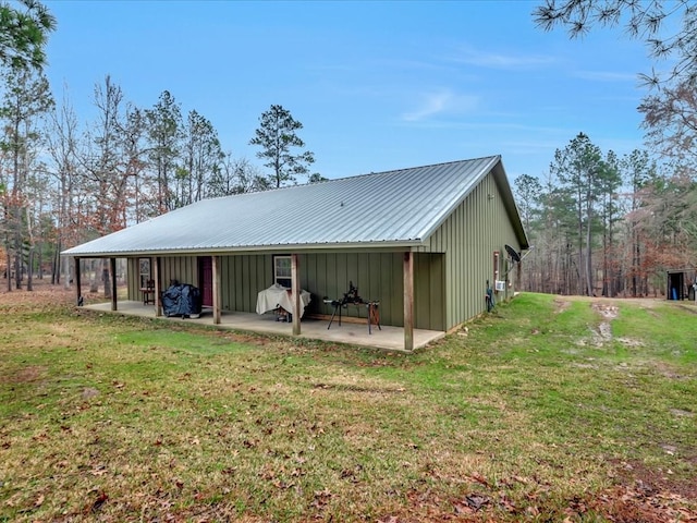 back of property with a patio area, board and batten siding, and a yard