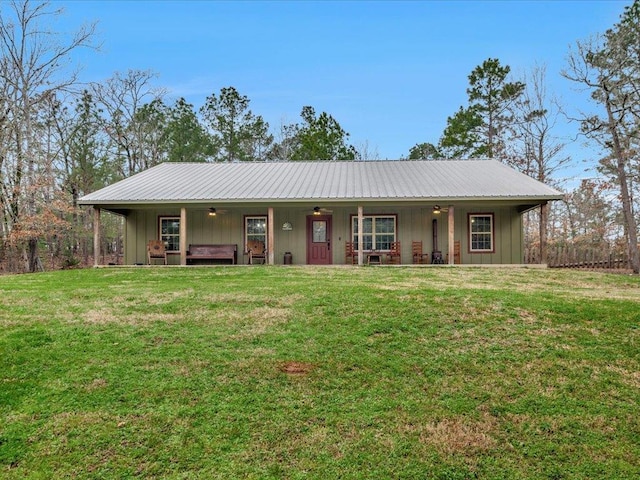 ranch-style home featuring board and batten siding, metal roof, and a front lawn