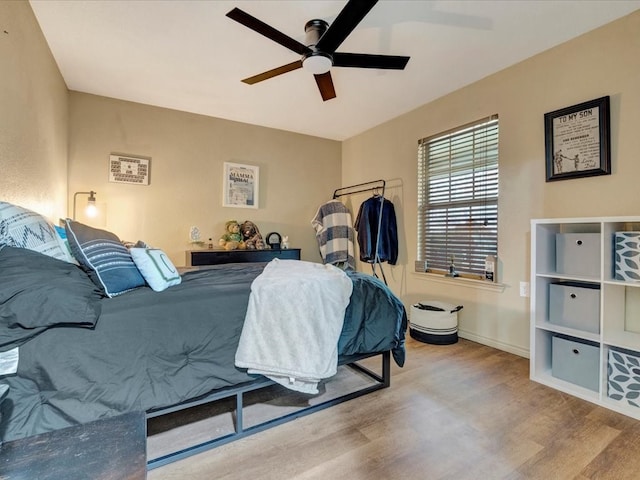 bedroom with light wood-style flooring, baseboards, and ceiling fan