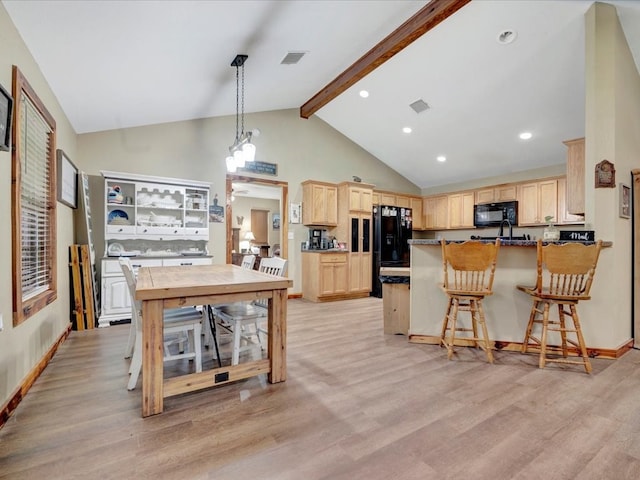 kitchen with visible vents, light brown cabinetry, black appliances, light wood finished floors, and a kitchen bar
