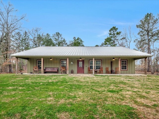 view of front facade featuring metal roof, board and batten siding, a front yard, and a jacuzzi
