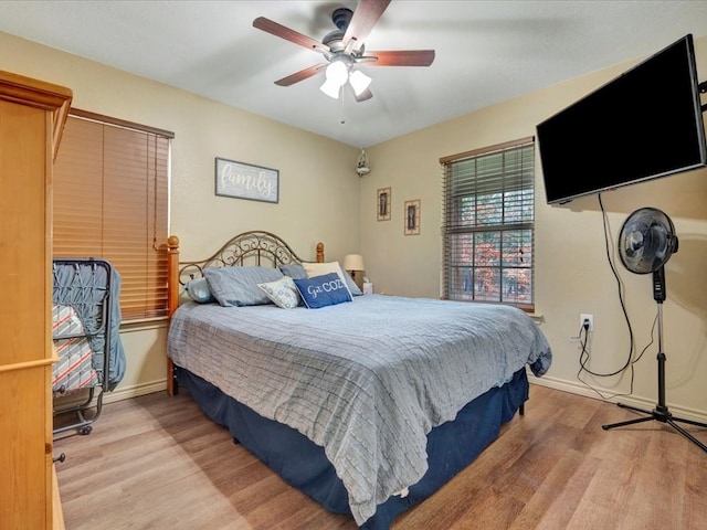 bedroom with light wood-style flooring, baseboards, and a ceiling fan