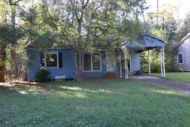 view of property hidden behind natural elements featuring a front lawn and a carport