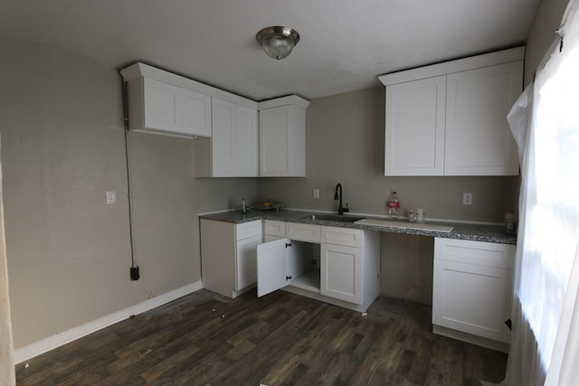 kitchen featuring white cabinets, stone counters, dark wood-type flooring, and sink