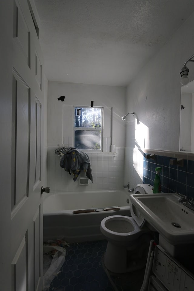 full bathroom with  shower combination, sink, tile patterned flooring, toilet, and tile walls