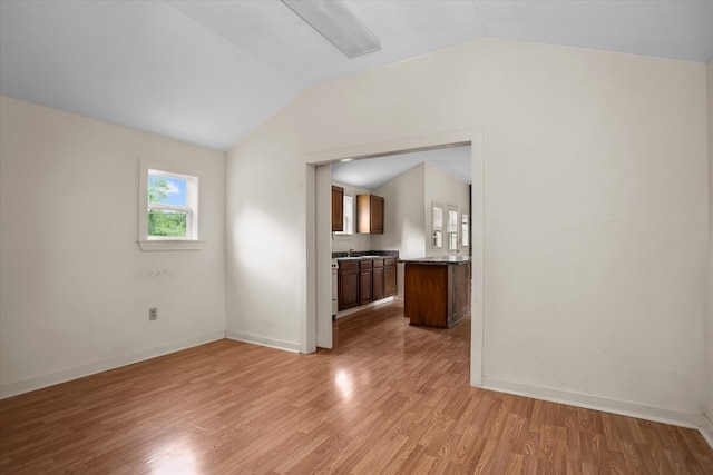 unfurnished living room with light wood-style floors, baseboards, and vaulted ceiling