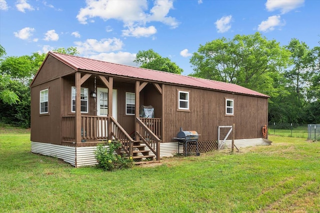 back of house with a lawn, fence, and metal roof