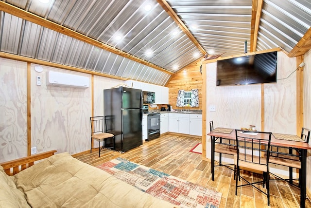 interior space with a wall mounted AC, black appliances, light hardwood / wood-style flooring, white cabinets, and lofted ceiling