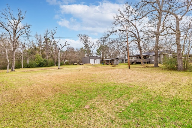 view of yard featuring a garage, an outbuilding, and driveway