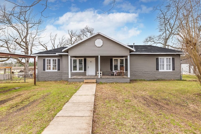 view of front of home with stone siding, covered porch, fence, and a front lawn