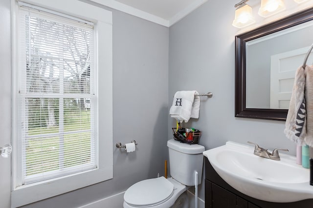 half bath with crown molding, vanity, toilet, and a healthy amount of sunlight