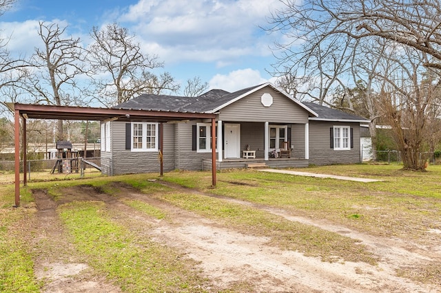 view of front of house with stone siding, dirt driveway, fence, and covered porch