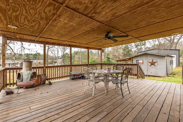 deck with an outbuilding, outdoor dining area, and ceiling fan