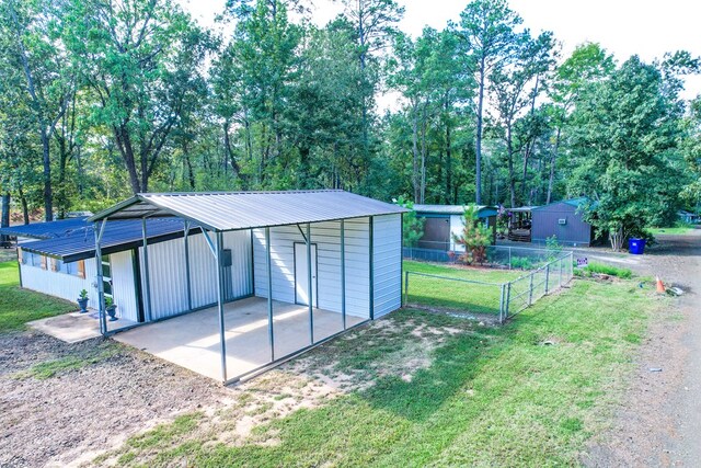 view of outdoor structure featuring driveway, fence, an outdoor structure, and a carport
