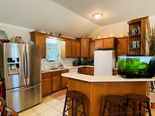 kitchen featuring lofted ceiling, a kitchen breakfast bar, white refrigerator, sink, and stainless steel fridge