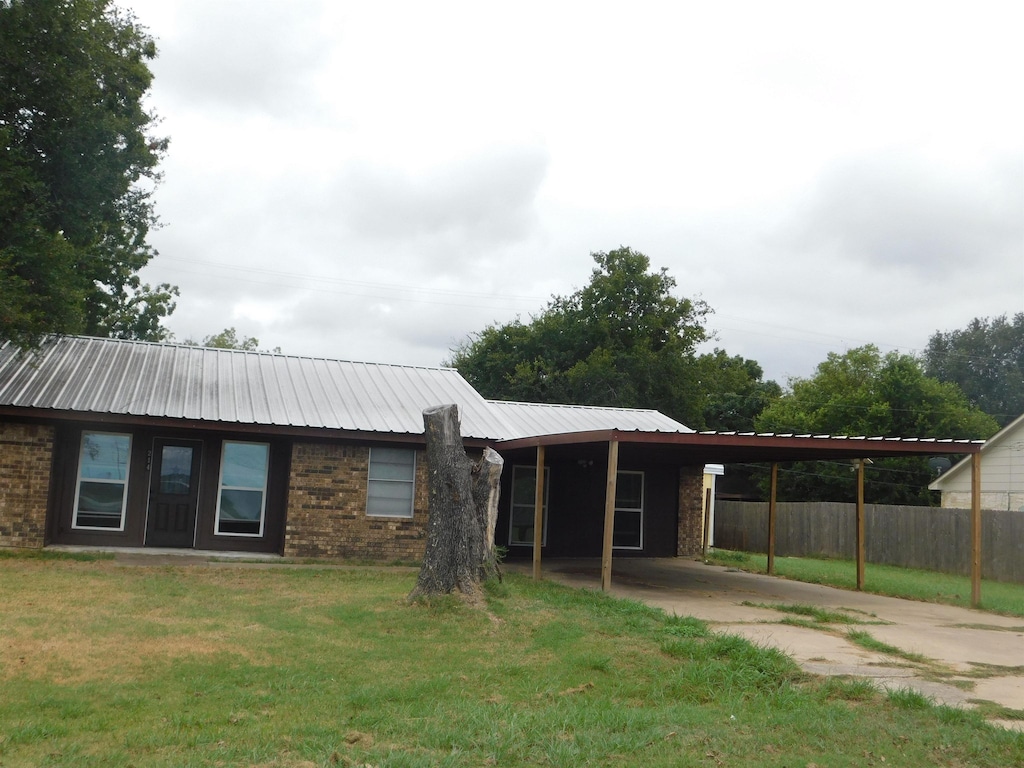 single story home featuring a front lawn and a carport