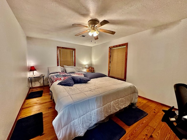 bedroom featuring a textured ceiling, light wood-type flooring, and ceiling fan