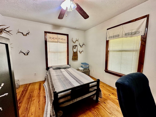 bedroom with ceiling fan, a textured ceiling, and hardwood / wood-style flooring