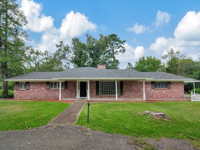 ranch-style home featuring covered porch and a front yard