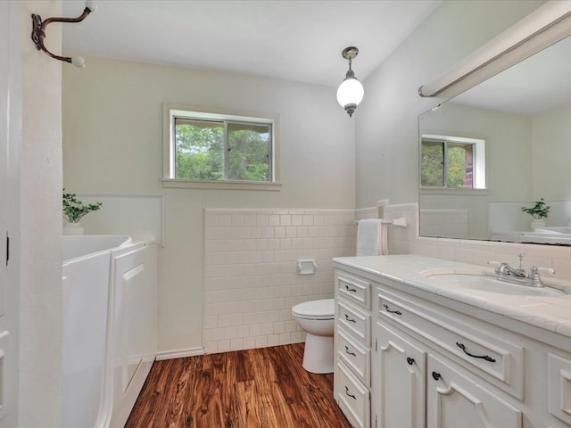 bathroom featuring wood-type flooring, vanity, toilet, and tile walls